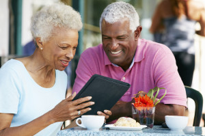 Senior Couple Using Tablet Computer At Outdoor Café